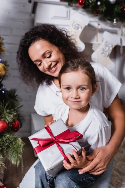 Madre Abrazando Hija Con Caja Regalo Cerca Pino Casa — Foto de Stock