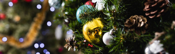 Панорамный снимок украшенной ели с рождественскими шарами и сосновыми шишками