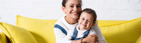 Panoramic Shot Mom Hugging Daughter Yellow Couch Looking Camera — Stock Photo, Image