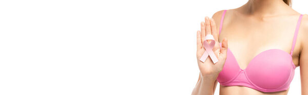 Panoramic shot of woman in bra showing pink ribbon of beast cancer awareness isolated on white