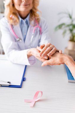 Masadaki pembe kurdelenin yakınındaki hastayı rahatlatacak seçici bir odaklanma.