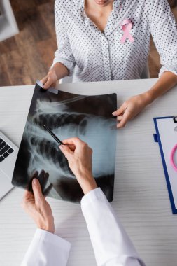 Klinikte hastanın önünde elinde kalem tutan doktorun kısmi görüntüsü