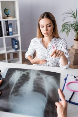 Seçici odak noktası, göğüs röntgeni olan doktorun yanındaki üzgün hastayı işaret etmek.
