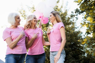 Düşük açılı kadınların pembe kurdeleleri göstermesi, balonları tutması