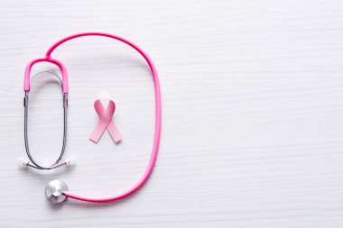 Top view of stethoscope and ribbon of breast cancer awareness on white wooden background clipart