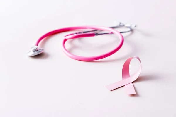 白色隔音听诊器和粉色缎带的表面水平 — 图库照片