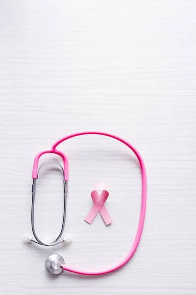 白木の背景に乳がんの認識と聴診器のリボンのトップビュー — ストック写真