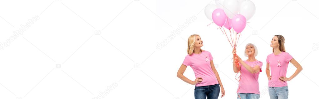 Panoramic shot of women with pink ribbons looking at balloons isolated on white