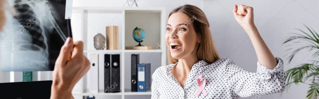 Panoramic shot of young adult woman with yes gesture near doctor with x-ray