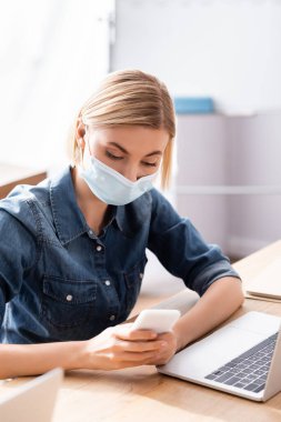 Sarışın yönetici ofisteki akıllı telefonda konuşuyor bulanık önplanda