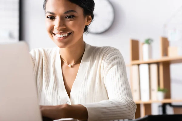 Szczęśliwa Afro Amerykańska Pracownica Pisząca Laptopie Biurze Zamazanym Pierwszym Planie — Zdjęcie stockowe
