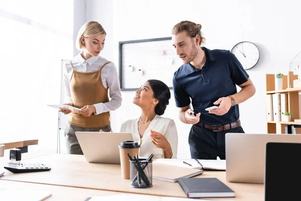 Mujer Afroamericana Sonriente Mirando Una Colega Sentada Mesa Con Portátil — Foto de Stock