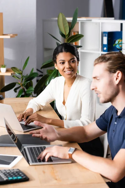 Sonriente Mujer Afroamericana Mirando Hombre Hablando Usando Portátil Oficina Primer — Foto de Stock