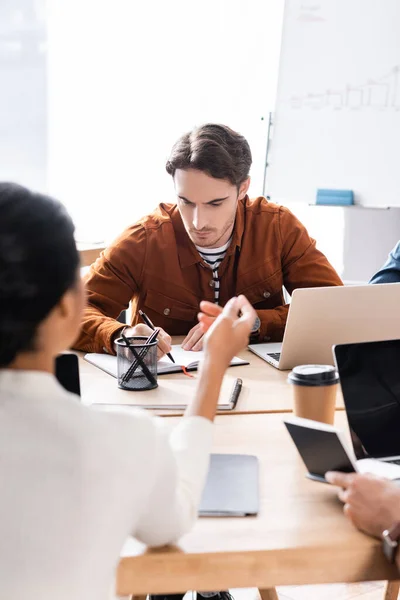 Konzentrierte Büroangestellte Schreibt Notizbuch Während Sie Schreibtisch Sitzt Während Eine — Stockfoto