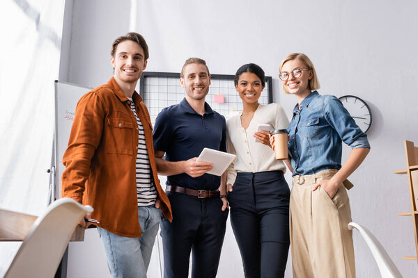 happy, young multicultural businesspeople looking at camera in office