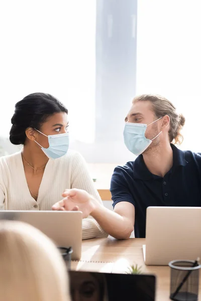 Junger Geschäftsmann Medizinischer Maske Zeigt Mit Der Hand Auf Laptop — Stockfoto