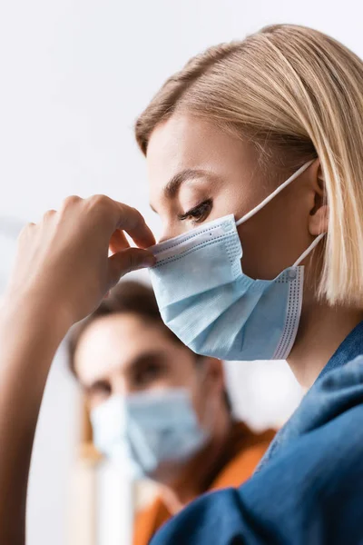 Blonde Businesswoman Fixing Medical Mask Colleague Blurred Background — Stock Photo, Image