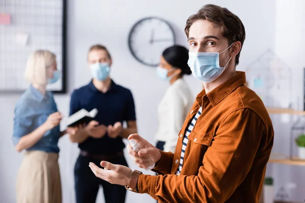 Giovane Manager Maschera Medica Che Tiene Disinfettante Mentre Guarda Fotocamera — Foto Stock