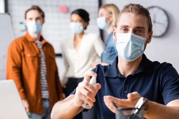 Giovane Uomo Affari Maschera Medica Spruzzando Disinfettante Sulle Mani Vicino — Foto Stock