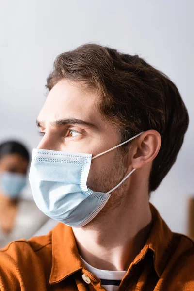 Young Businessman Medical Mask Looking Away Office Blurred Background — Stock Photo, Image