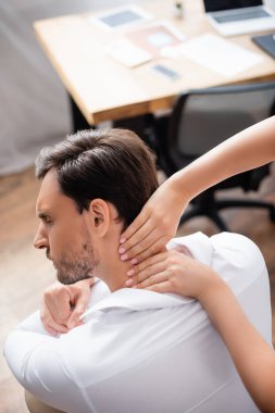 Masözün genel görünüşü bulanık arka planda ofisteki acılı boyun masajı.