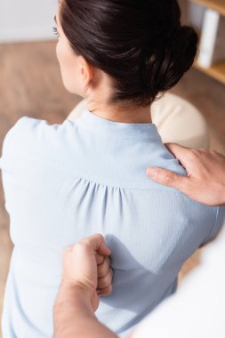 Bulanık arka planda iş kadınına masaj yapan masörün yakın görüntüsü.