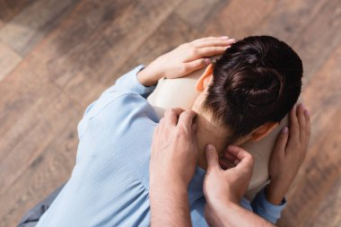 Masaj terapistinin, esmer bir iş kadınının boynuna, dokulu arka planda masaj yapması.