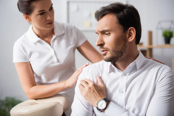 Masseuse Staan Achter Kijken Naar Zakenman Met Hand Pijnlijke Schouder — Stockfoto