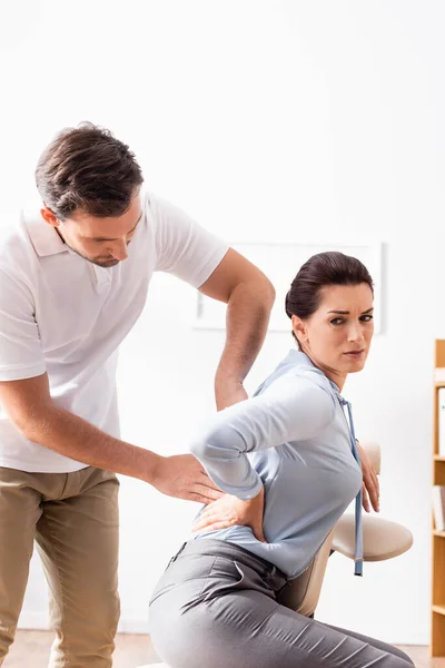 Masajista Masajeando Dolorosa Espalda Mujer Negocios Con Mano Cadera Sentado — Foto de Stock