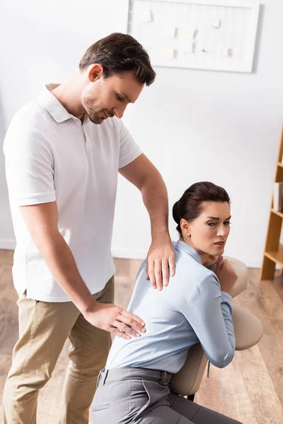Massagista Sorridente Massageando Costas Dolorosas Cliente Feminino Sentado Cadeira Massagem — Fotografia de Stock