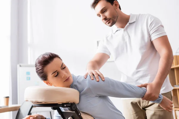 Massage Therapist Massaging Hurting Arm Female Client Sitting Massage Chair — Stock Photo, Image