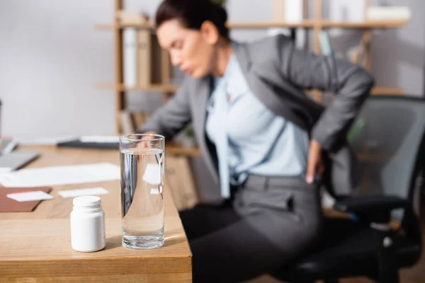 Glass Water Medication Table Blurred Businesswoman Hurting Back Background — Stock Photo, Image