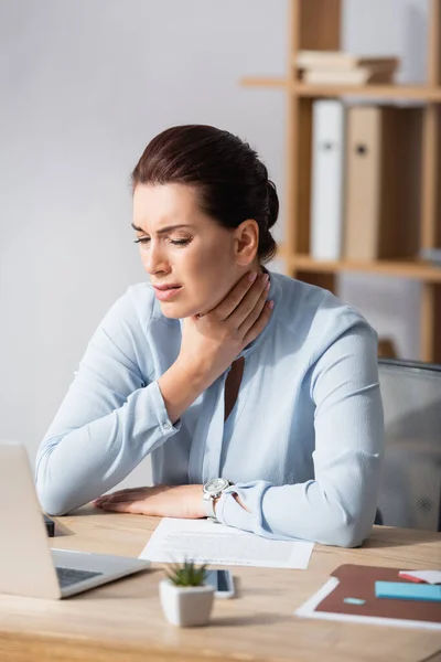 Brunett Affärskvinna Med Handen Smärtsam Hals Sitter Arbetsplatsen Suddig Bakgrund — Stockfoto