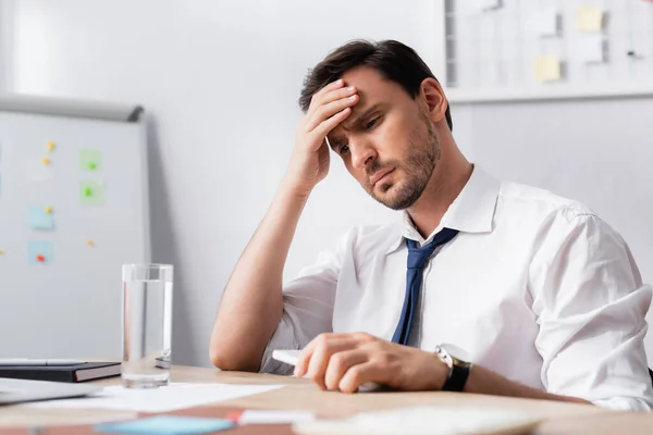 Geschäftsmann Mit Kopfschmerzen Hält Smartphone Der Hand Sitzt Arbeitsplatz Mit — Stockfoto