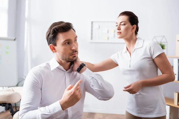 Masseuse Looking Painful Neck Businessman Pointing Finger While Sitting Massage — Stock Photo, Image