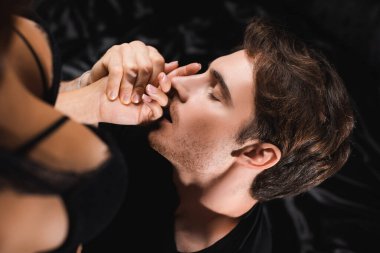 Genç adam ön planda sütyenli seksi kız arkadaşının elini öpüyor. 