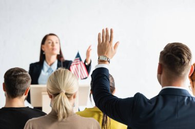 Politik kışkırtıcı, eli havada arka planda bulanık bir adamı işaret ediyor.