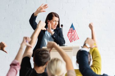 shocked speaker standing in front of voters showing thumbs down in conference hall clipart