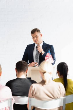Konferans salonunda seçmenlerin önünde duran kendinden emin bir siyasi kışkırtıcı, bulanık önplan