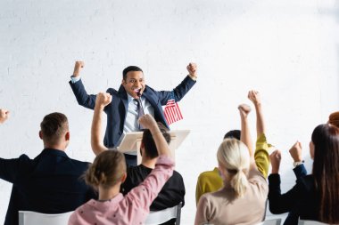 Konferans salonunda seçmenlerin önünde bulanık bir şekilde dururken kazanan jesti gösteren heyecanlı Hintli konuşmacı