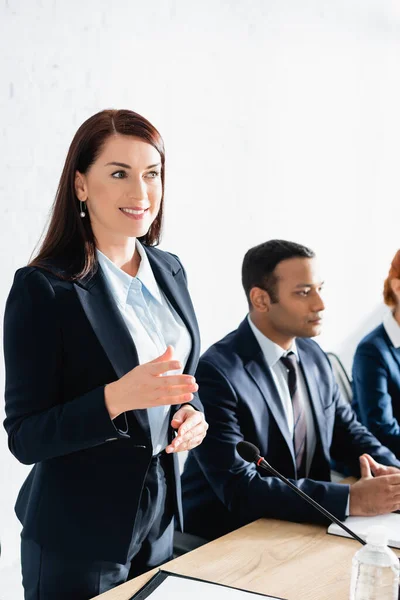 Sorridente Politico Donna Gesticolare Mentre Piedi Sala Riunioni Con Colleghi — Foto Stock