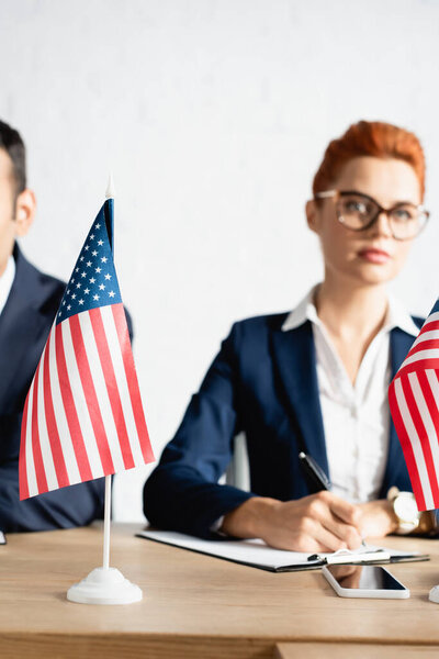 Маленькие американские флаги на столе с размытыми людьми на заднем плане