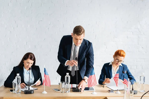 Man Formal Wear Touching Microphone While Leaning Forward Female Colleagues — Stock Photo, Image