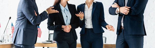 Cropped view of multicultural politicians gesturing while standing in boardroom, banner