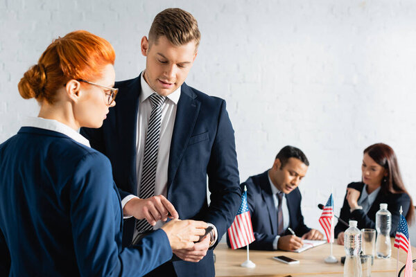 man pointing with finger near colleague while party members working on blurred background