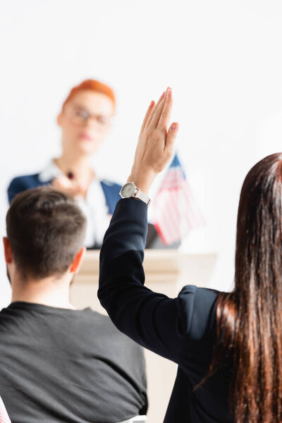candidate on blurred background looking at woman with raised hand in conference hall
