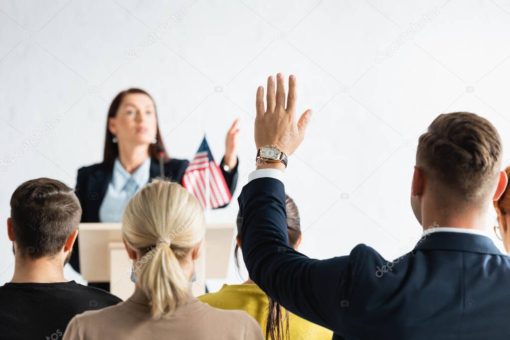 political agitator pointing with hand at man with raised hand on blurred background