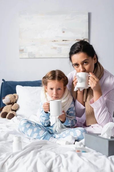 Hastalıklı Anne Kız Yatakta Otururken Sıcak Çay Içiyor — Stok fotoğraf