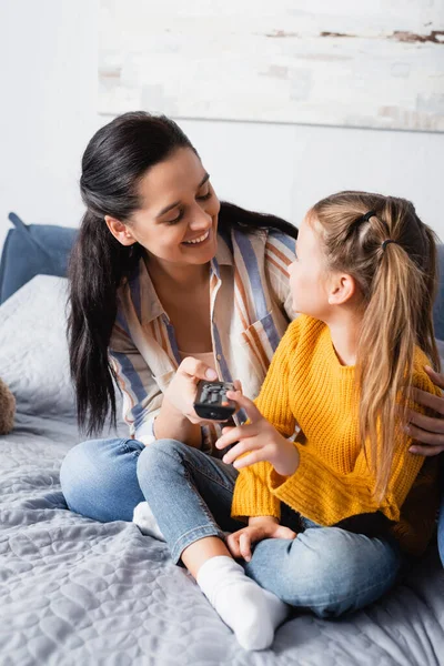 Lycklig Kvinna Omfamna Dotter Medan Håller Fjärrkontroll — Stockfoto