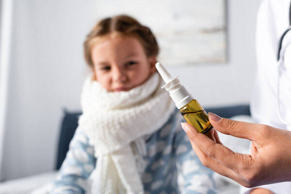 doctor holding nasal spray near sick girl on blurred background